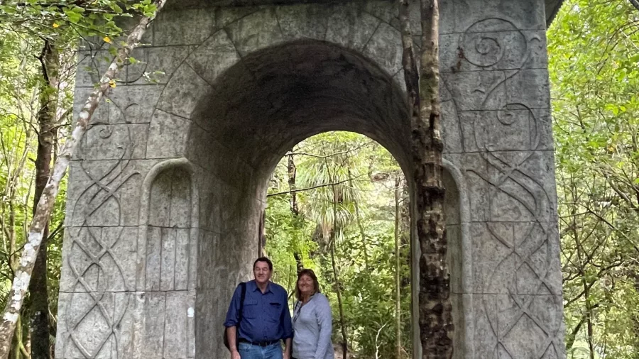 Two people standing under the Elven archway replica at Rivendell in Kaitoke Regional Park