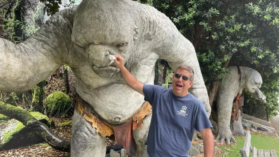Man playfully pretending to pick troll statue’s nose at Wētā Cave