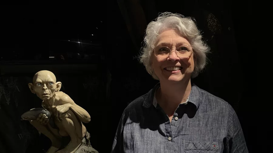 Visitor smiling beside Gollum statue holding a fish at Wētā Cave