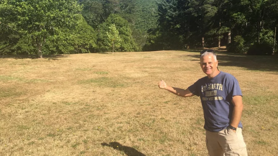 Man pointing at the grassy field that served as the Gardens of Isengard filming location in Lord of the Rings