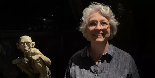 Visitor smiling beside Gollum statue holding a fish at Wētā Cave