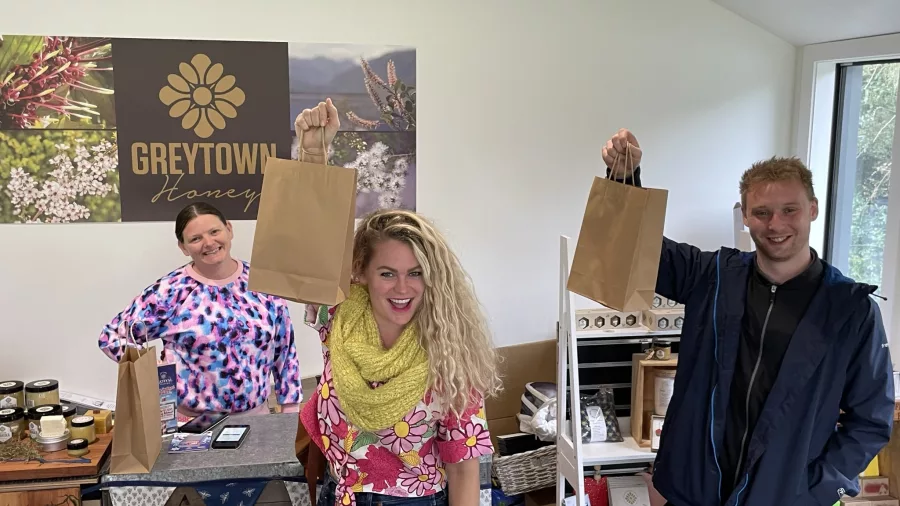 Guests holding up paper bags after shopping at Greytown Honey