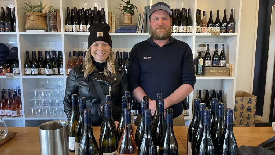 Two staff members behind a wine tasting counter with bottles on display at Moy Hall
