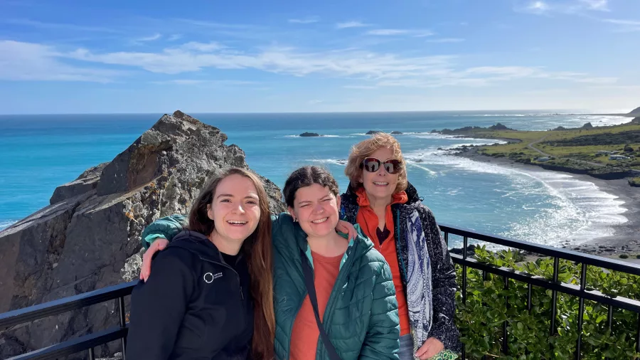 Group posing below Cape Palliser Lighthouse with ocean views