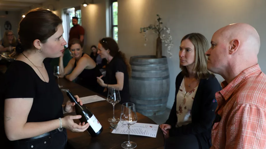 Wine host sharing tasting notes with guests at Poppies Martinborough cellar door
