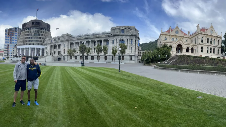 Two men posing on the lawn in front of the Parliament Buildings in Wellington