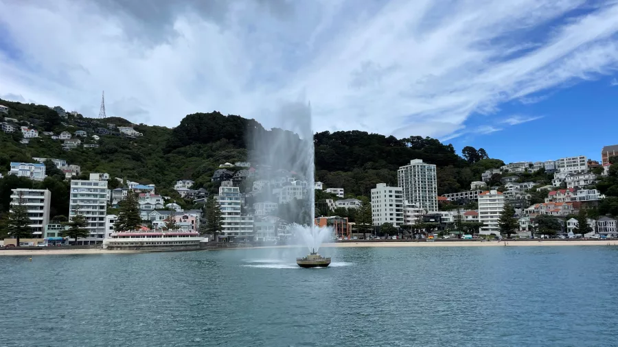 Oriental Bay fountain spraying water with hillside homes in the background
