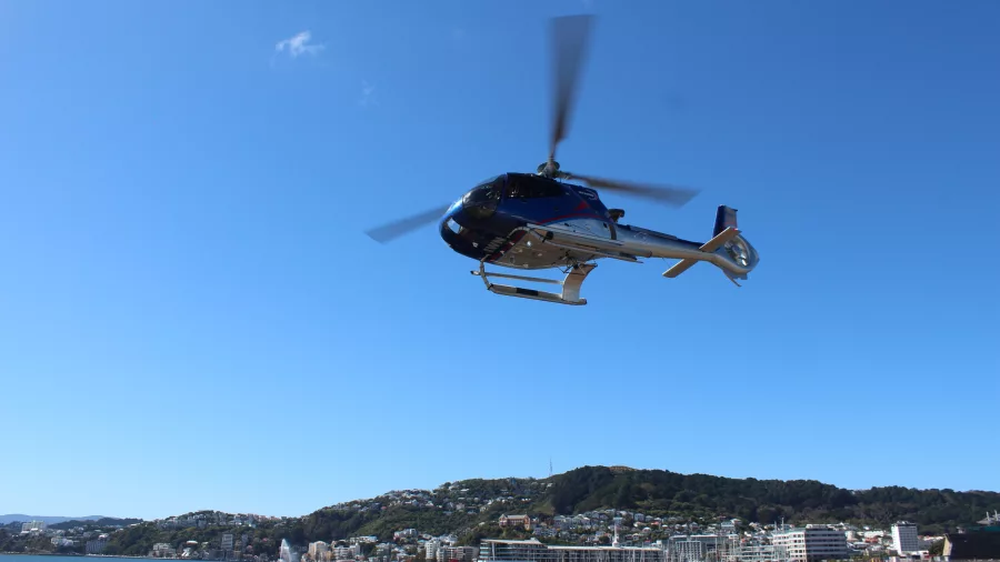 Helicopter taking off above Oriental Bay with Wellington Harbour in view
