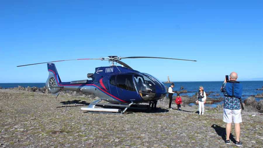 Helicopter landing on Wellington’s South Coast with passengers disembarking near the sea