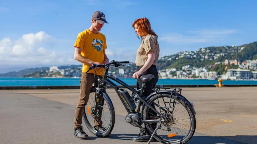 Guide showing a woman how to use an electric bike during a Wellington waterfront tour
