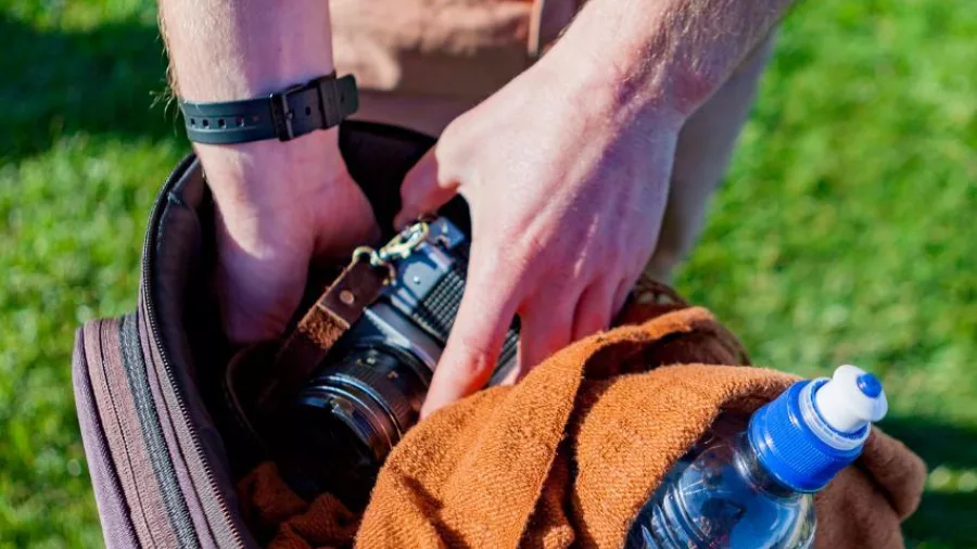 Person packing a camera and water bottle into a bike bag during a Wellington guided bike tour