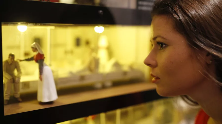 Close-up of a visitor observing a miniature nurse and soldier diorama at the Gallipoli exhibition in Te Papa, Wellington.