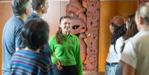 Visitors listening to a guide beside the traditional Māori waharoa on the Māori Highlights Tour at Te Papa Wellington