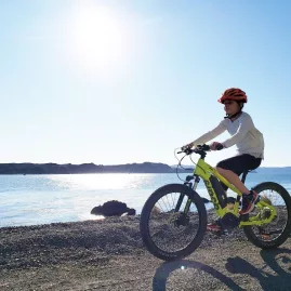 Child riding a bright green e-bike along Pencarrow Coast in Wellington on a sunny day