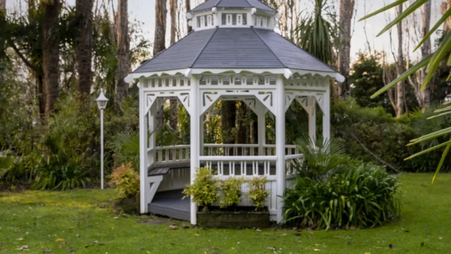 White gazebo in the garden of Wallaceville Country Hotel surrounded by trees and lush greenery