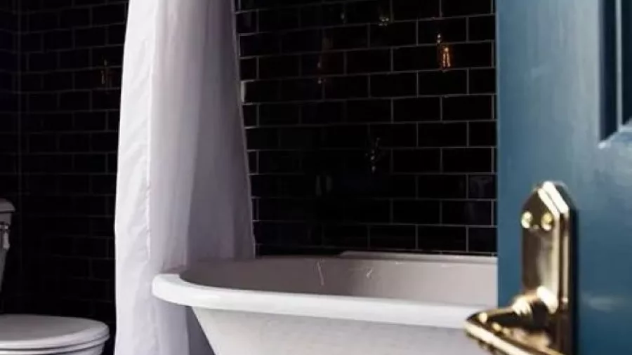 Vintage-style bathroom at The Royal Hotel with black tiles and clawfoot tub