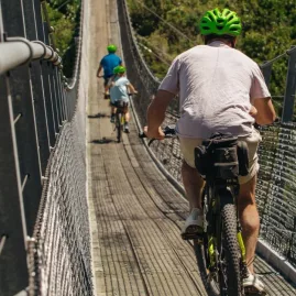 Group of cyclists riding across a long swingbridge on the Remutaka Cycle Trail