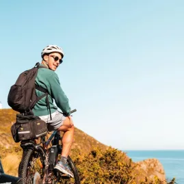 Cyclist on a mountain bike pausing at a coastal lookout near Pencarrow