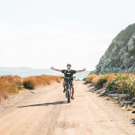 Cyclist riding hands-free along the Pencarrow coastal trail in Wellington