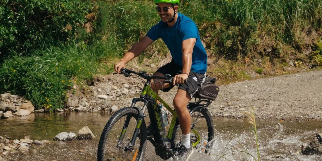 Cyclist crossing a shallow stream along the Remutaka Cycle Trail in the rail trail section