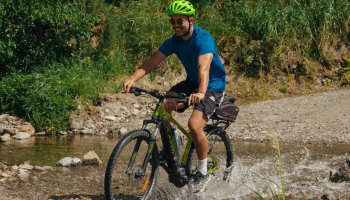 Cyclist crossing a shallow stream along the Remutaka Cycle Trail in the rail trail section