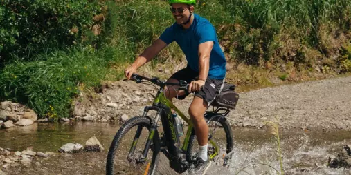 Cyclist crossing a shallow stream along the Remutaka Cycle Trail in the rail trail section