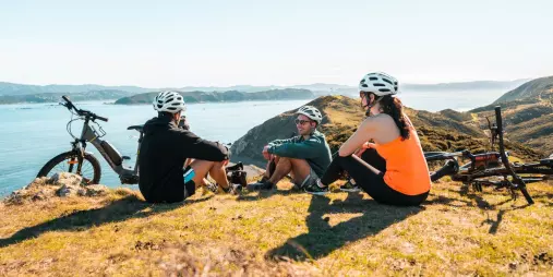 Cyclists taking a break with scenic coastal views on the Remutaka Cycle Trail