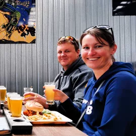 Couple enjoying burgers and beer paddles during a craft beer tour in Wellington