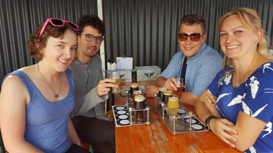 Group of friends enjoying a craft beer tasting flight at a Wellington brewery