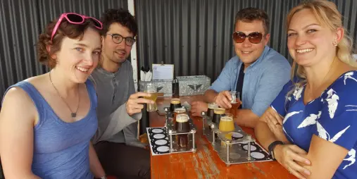 Group of friends enjoying a craft beer tasting flight at a Wellington brewery