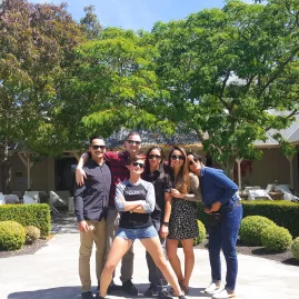Group of friends posing under lush trees at a Martinborough vineyard courtyard