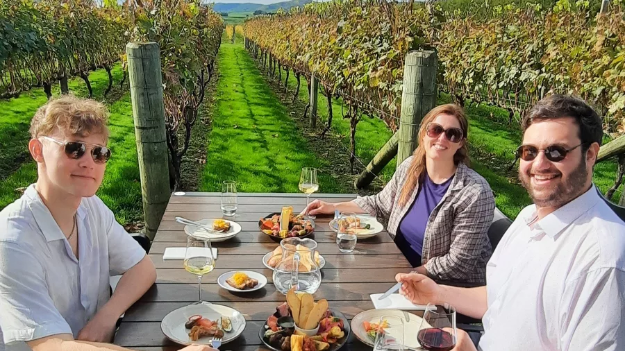 Three travellers enjoying vineyard lunch with wine in Martinborough