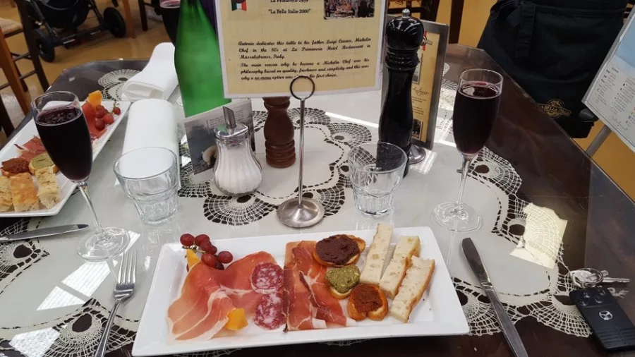 Antipasto plate with cured meats, bread, and wine at La Bella Italia in Petone