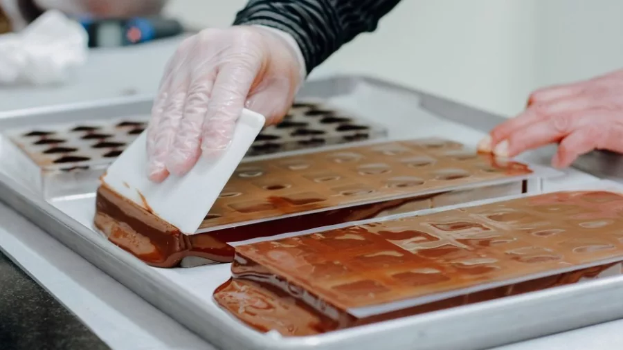 Chocolate being poured and spread into moulds at The Chocolate Story in Petone