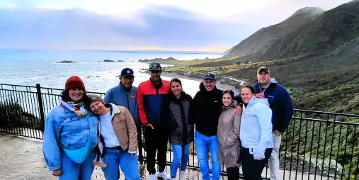 Group of travellers posing by the coast near Wellington with sea cliffs and sunset