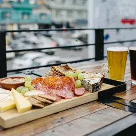 Cheese and charcuterie platter with two pints of beer on a wooden table at Fortune Favours in Wellington