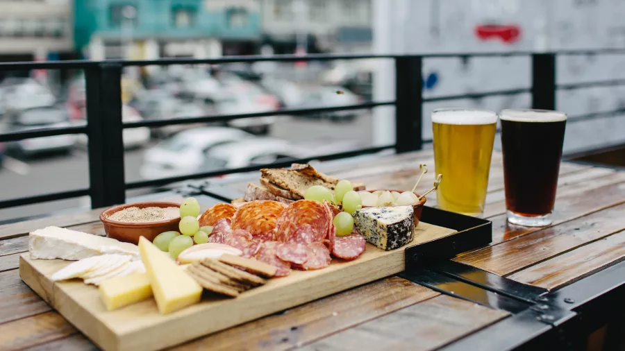 Cheese and charcuterie platter with two pints of beer on a wooden table at Fortune Favours in Wellington
