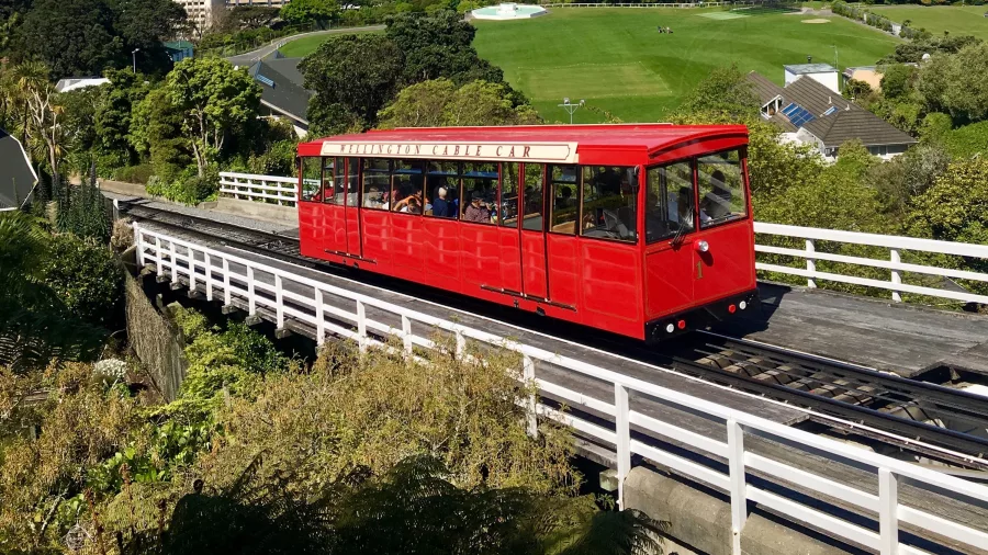Red Wellington Cable Car overlooking city skyline and harbour on a clear day