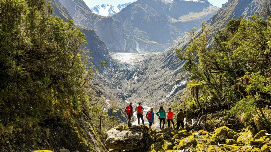 Group of hikers taking in stunning glacier valley views framed by alpine peaks.