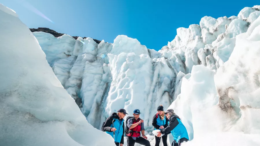 Guided tour group explores icy terrain at Fox Glacier with expert guide