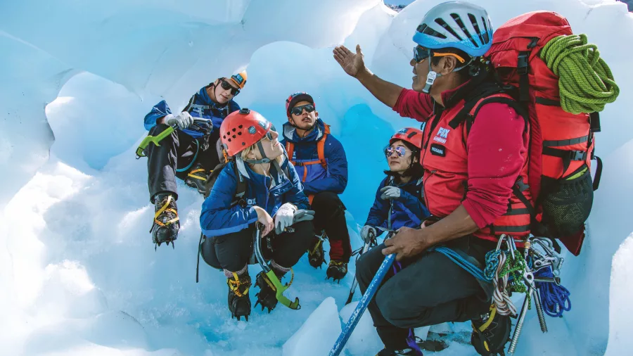A guide briefs climbers on glacier techniques inside an ice cave.