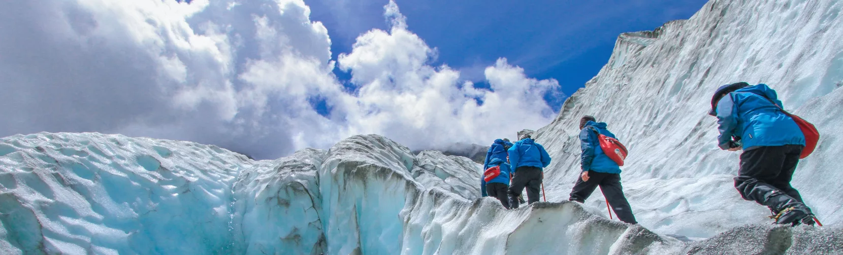 Group climbing the ice walls of Franz Josef Glacier with crampons and guides