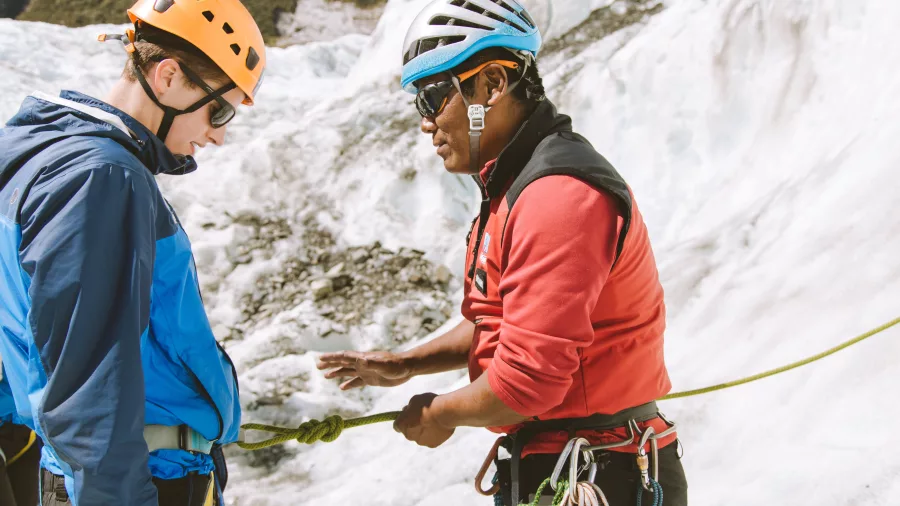 Guide demonstrates a climbing technique during a Fox Glacier ice climbing session.