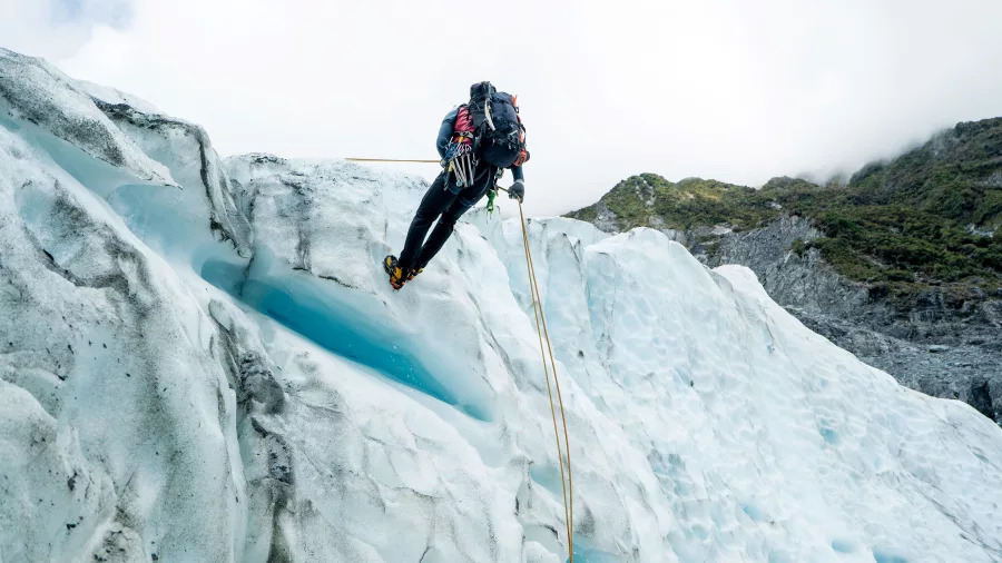 Ice climber descending a crevasse on Fox Glacier during a helihike on the West Coast