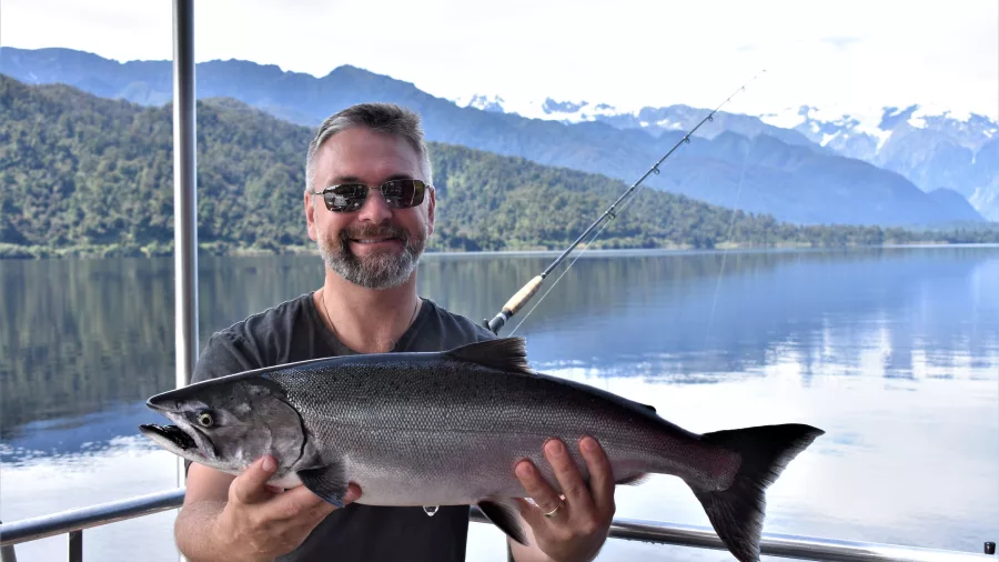 Man holding freshly caught salmon on Lake Mapourika near Franz Josef