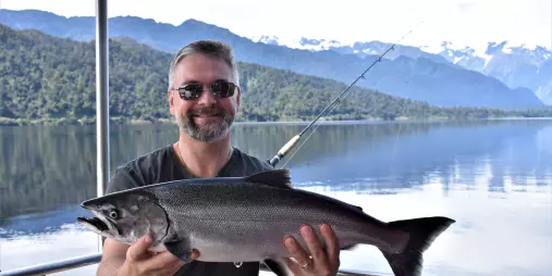 Man holding freshly caught salmon on Lake Mapourika near Franz Josef