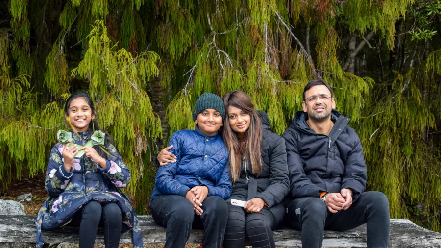 Family sitting on a bench surrounded by lush native forest during Franz Josef Kayak and Walk tour in New Zealand