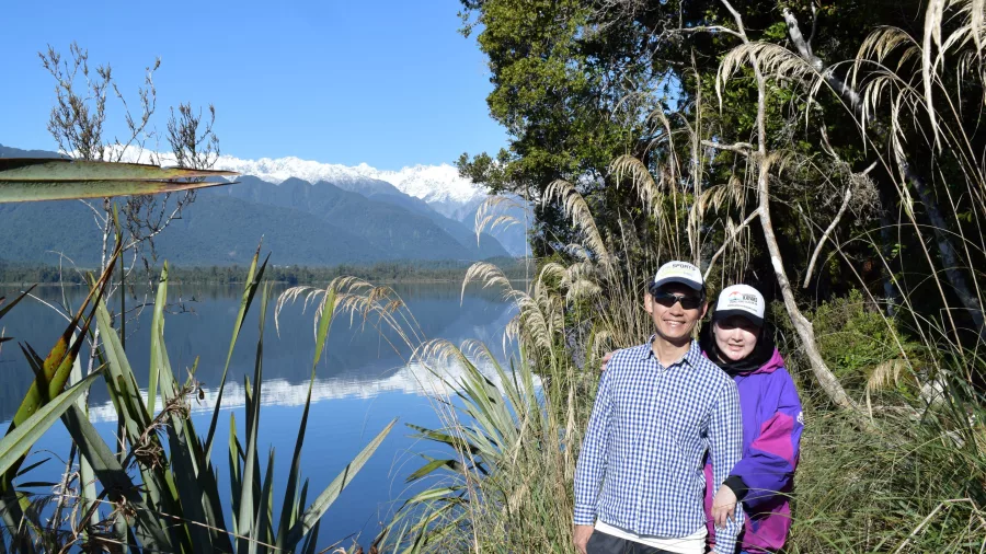 Couple posing by Lake Mapourika with snow-capped Southern Alps in background