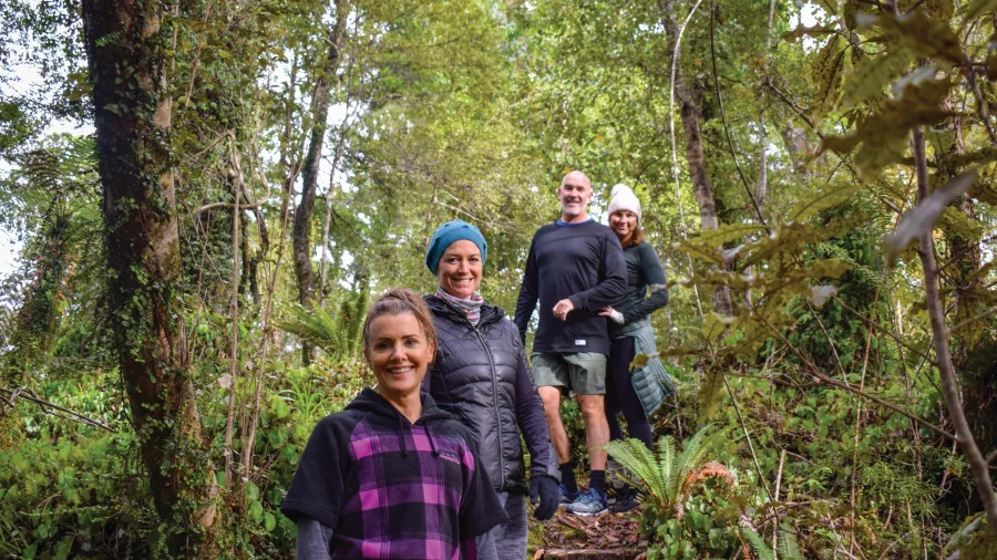 Group of hikers smiling on a forest trail during the Kayak and Walk tour in Franz Josef, New Zealand
