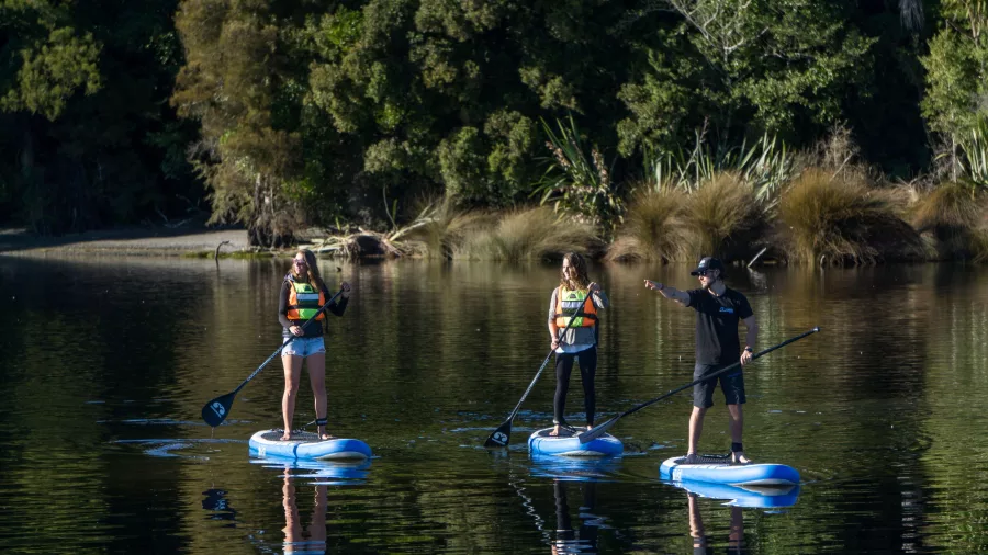 SUP guide giving instructions during a paddleboarding tour on Lake Mapourika